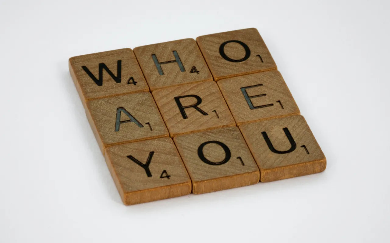 Scritta "Who are you" fatta su quadratini di legno, tipo tavola periodica