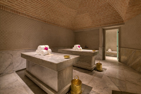 Αν authentic character hammam room made of marble in earth tones, 2 marble beds with white towels on them 