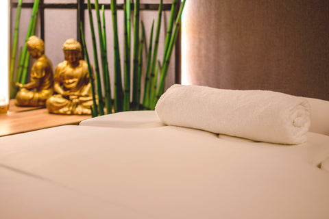 A gold Buda and a treatment bed with a towel on it in Swisslines treatment room.