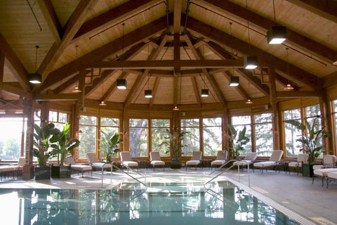 indoor heated pool, with white sunbeds in a luxurious spa with a wooden canopy and large windows