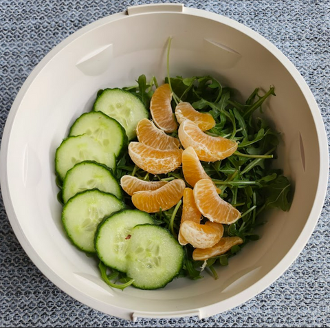 Salad base in Lotus Bowl with arugula, oranges, and cucumbers