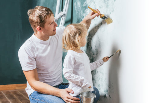 Vater und Tochter streichen eine Wand