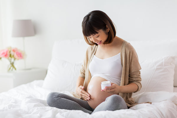 Pregnant woman applies moisturizer to her skin