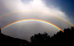 A double rainbow appearing over some landscape with clouds in the background