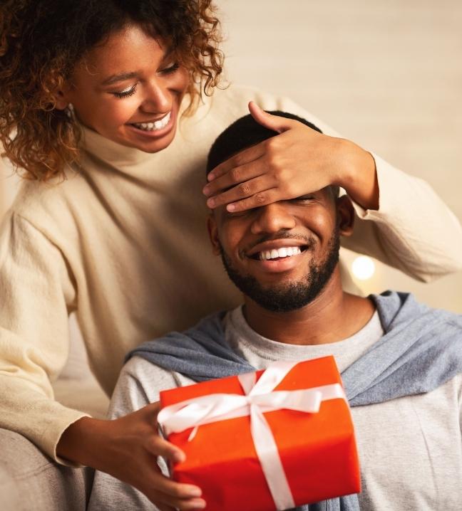 Une homme souriant recevant un cadeau surprise