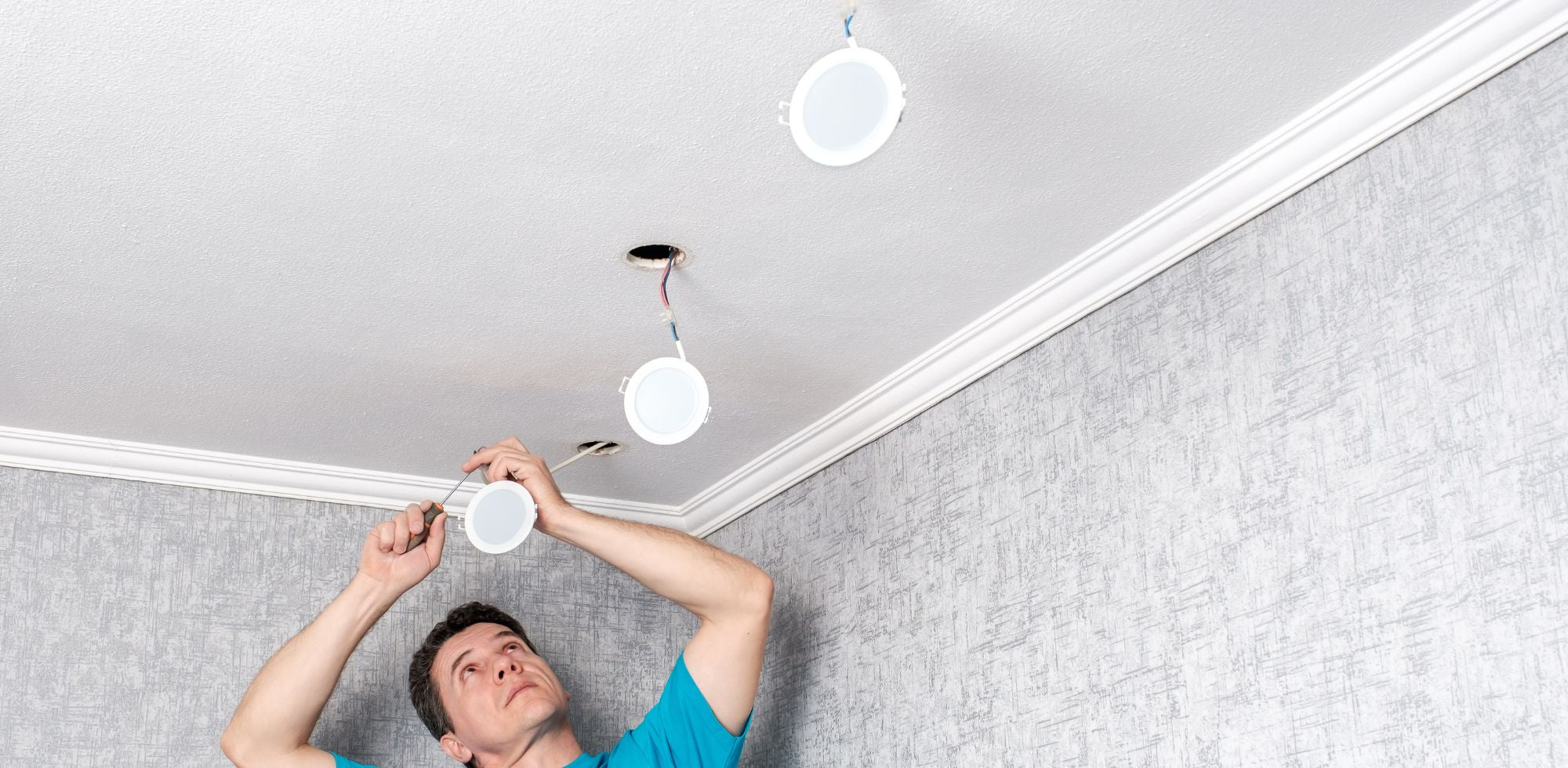 Un homme installant un spot sur le plafond