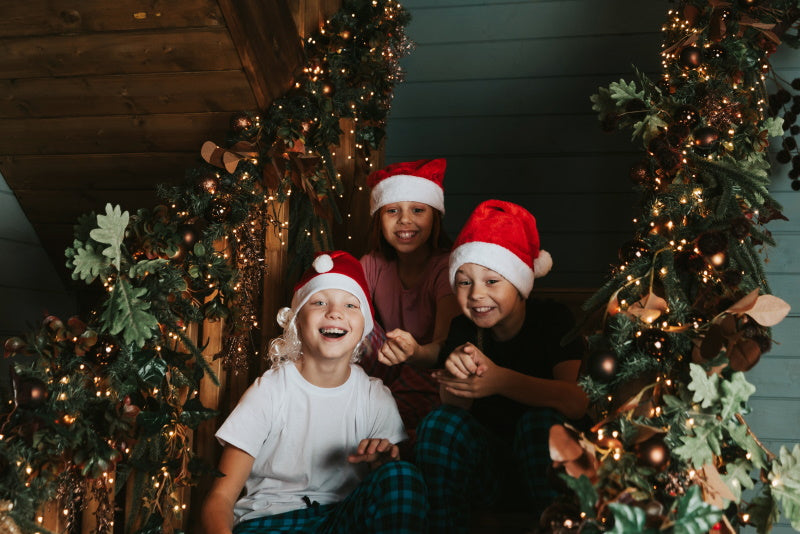 Des enfants avec bonnet de noël sur un escalier