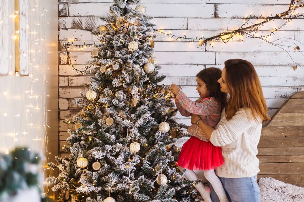 Une femme et un enfant décorant un sapin de Noël