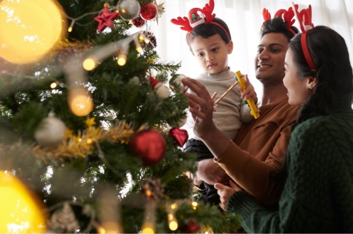 Une famille avec un enfant décorant un sapin de Noël
