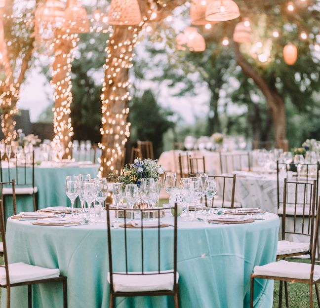 Table de mariage avec des guirlandes accrochées aux arbres