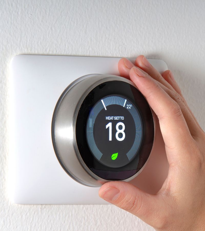 Une main sur un thermostat connecté