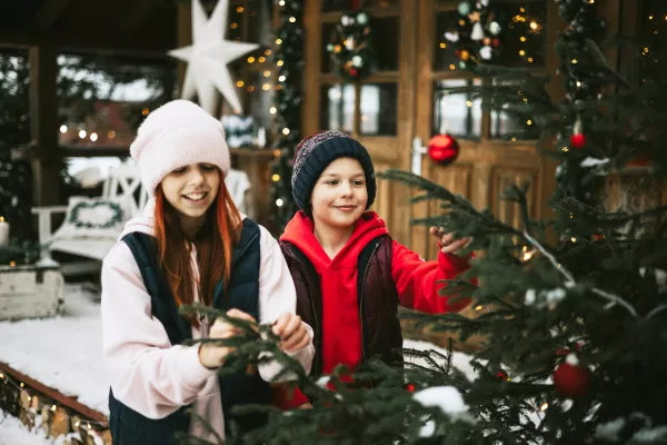 Deux enfants décorant un sapin extérieur