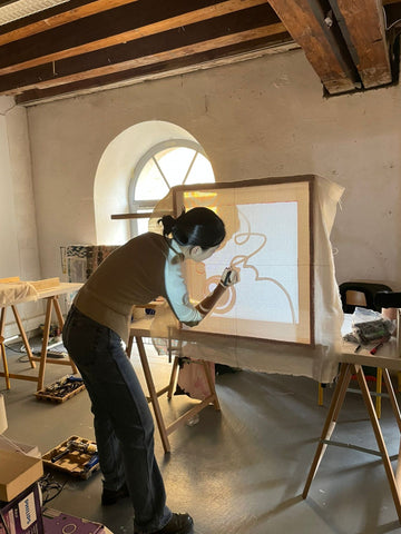 person projecting a drawing onto a stretched canvas