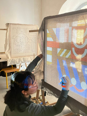 Persona proyectando un dibujo sobre un lienzo estirado.