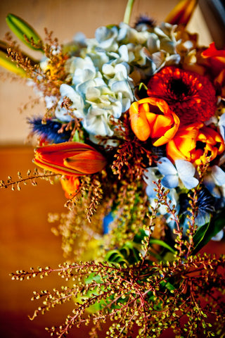 Closeup of the orange and blue color scheme wedding reception flowers by gorgeous and green