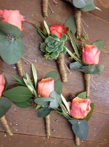 Simple boutonnieres featuring garden roses in a lovely coral color, and a succulent for the groom
