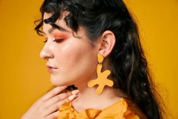 Pendientes llamativos de cuero inspirados en Marigold Matisse en una mujer joven