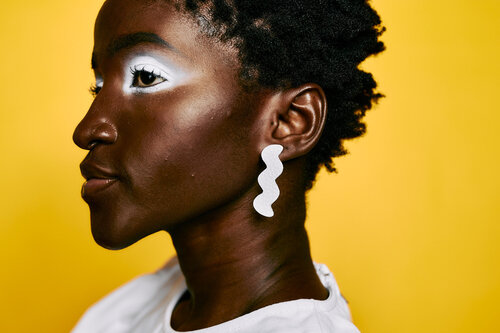 Una mujer joven con cabello corto usa aretes con rastro de luz blanca.