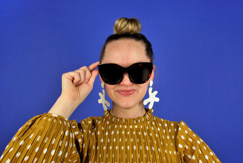 Alaina styles the white Point Move earrings with oversized sunglasses and a sleek topknot. 