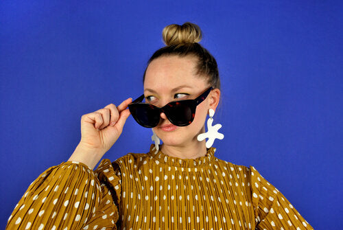 Alaina styles the white Point Move earrings with oversized sunglasses and a sleek topknot. 