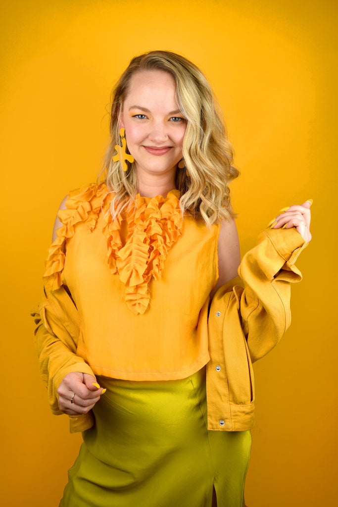 Blonde Alaina can’t stop smiling in a shades of yellow outfit complete with marigold point move earrings from Cold Gold.