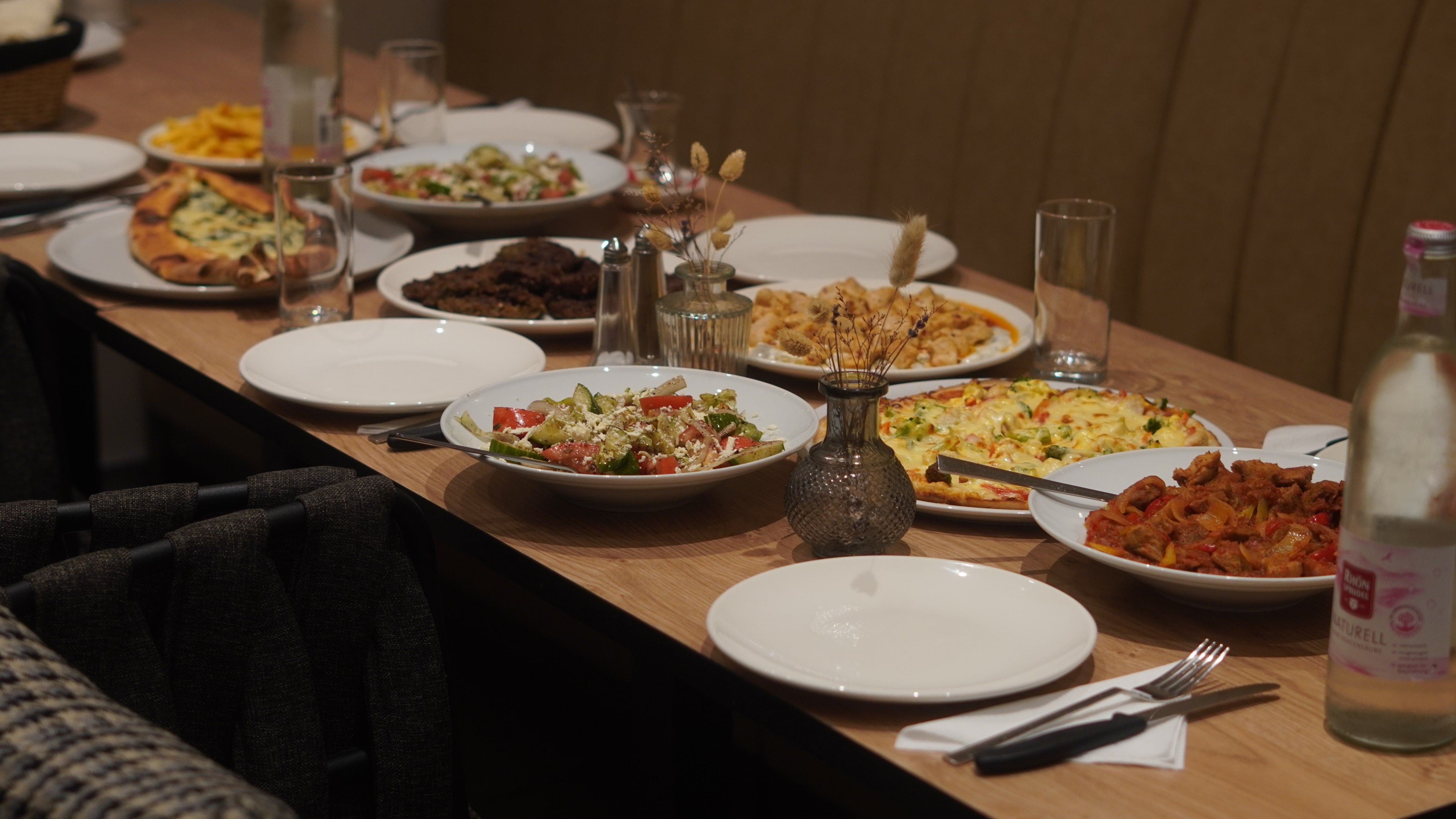 Eiche-Farbiger Tisch mit Teller und Besteck gefüllt mit türkischem Essen (sieht aus wie Catering) Adana, Sac Kavurma & Salat in einem türkischen Cafe Restaurant