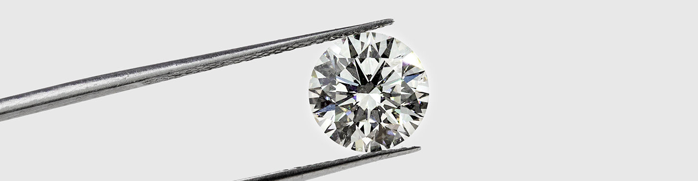 round diamond held by long tweezers