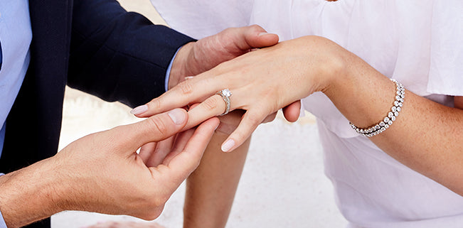 man putting engagement ring on hand