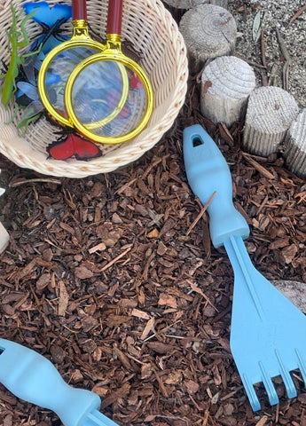 Basket of plastic bugs with magnifying glass and Rutabaga Garden Tools Hand Rakes.