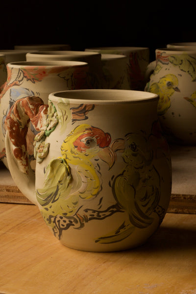 Shows an unglazed work in progress painted mug of the extinct Carolina Parakeet