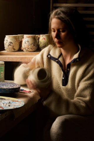 Artist working on mugs in the studio