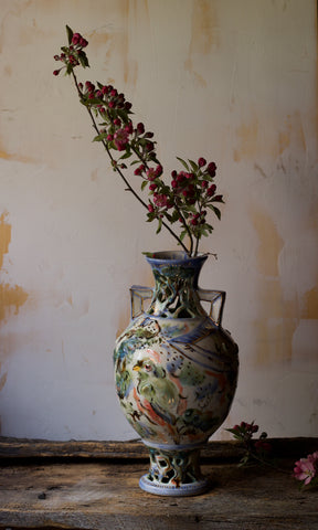 Tall vase against neutral off white background with apple blossoms 