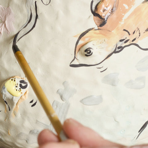 Close up of a bird being painted on a clay surface.