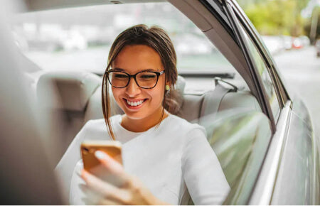 Mujer enviando un mensaje de texto mientras viaja en un taxi.