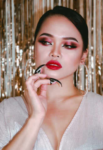 an asian woman with cranberry smokey eyeshadow and red lipstick posing for the the camera