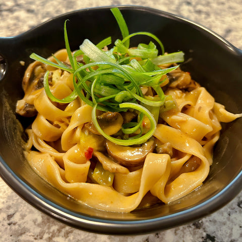 a photo of spicy noodles and mushrooms in a bowl