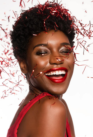 an african american woman wearing red lipstick, dark smokey eyeshadow surrounded by falling red confetti