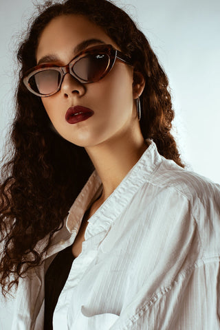 a woman posing with sunglasses and dark berry lipstick