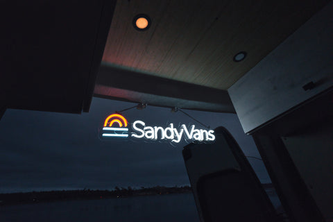 sandy vans neon sign lit up at night from inside van