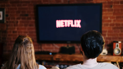 A couple sitting on a couch with Netflix on the TV in front of them