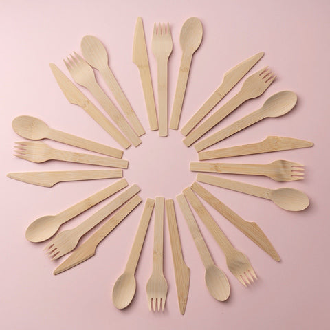 A circle of bamboo silverware on a pink background