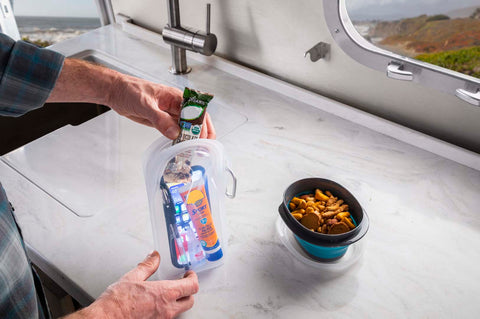 A person filling up a reusable bag with snacks