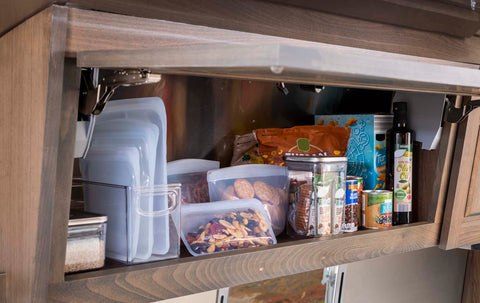 A storage cabinet in an Airstream with the door open showing items sitting in there