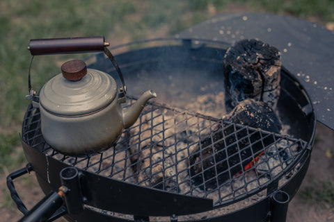 A teapot sitting over a campfire