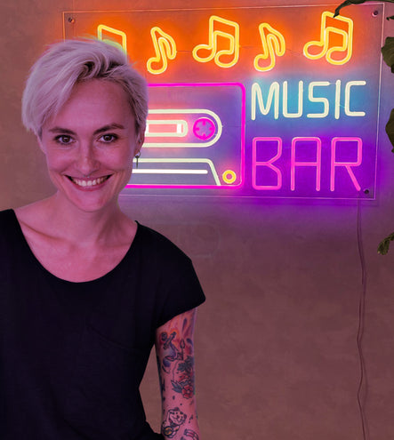 A woman standing in front of a 'Music Bar' Neon sign.