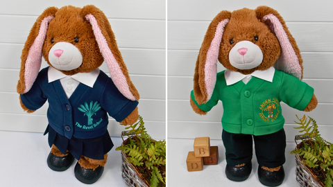 Two Build a Bear Teddy Bears. The teddy bear on the left is wearing a blue school uniform comprising of a teddy bear skirt, teddy bear polo t-shirt and a teddy bear school cardigan. The teddy bear on the right is wearing a green teddy bear school cardigan, white teddy bear polo t-shirt and black teddy bear pants.