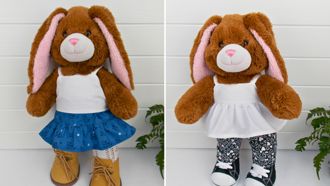 2 x Build a Bear Teddy Bears. The teddy bear on the left is wearing a white camisole top, blue skirt, white tights & sand coloured boots. The teddy bear on the right is wearing a white peplum top, back& pink patterned leggings, & black & white converse style boots