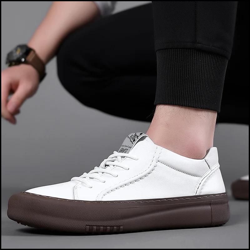 White leather sneakers for men with brown soles, worn by a person with black pants, for a sharp look