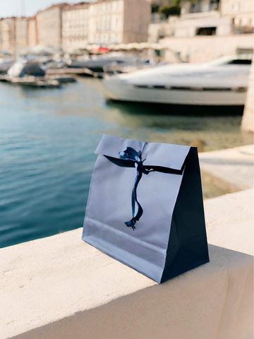 paquet en carton avec un ruban posé sur un muret dans un port de provence
