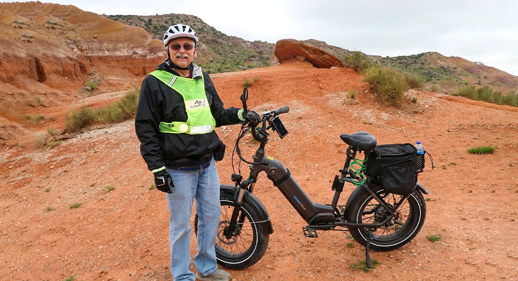 An elderly man is standing next to his electric bike